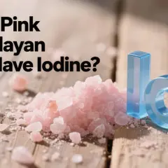 Góra różowej soli himalajskiej na drewnianym blacie, obok niebieskie litery "I" i "O", sugerujące pytanie: czy sól himalajska jest jodowana?
