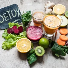 Kolorowe soki i warzywa na drewnianym tle. Tabliczka z napisem "DETOX" sugeruje, że te składniki pomagają w walce z tym, co zakwasza organizm.