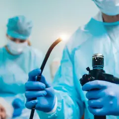 Lekarz w niebieskiej masce i fartuchu przygotowuje endoskop do badania, które może pomóc w diagnostyce przełyku Barretta.