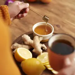 Ręka dodaje miód do herbaty z imbirem i cytryną. Choć imbir ma wiele zalet, warto pamiętać o jego szkodliwości w nadmiarze.