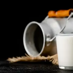 Szklanka mleka obok metalowego konewki. Czy to colostrum? To pierwszy, bogaty w składniki odżywcze pokarm matki.
