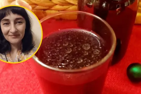 Kiedy pić zakwas z buraka? Kobieta uśmiecha się obok szklanki z ciemnym napojem i butelki.