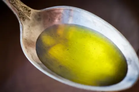 Łyżka z płynnym, żółtym olejem lnianym, który może pomóc w obniżeniu cholesterolu.