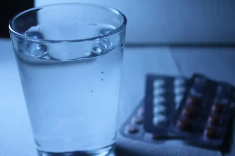 Szklanka wody obok opakowań leków. Czy to melatonina i alkohol, czy tylko złudzenie?
