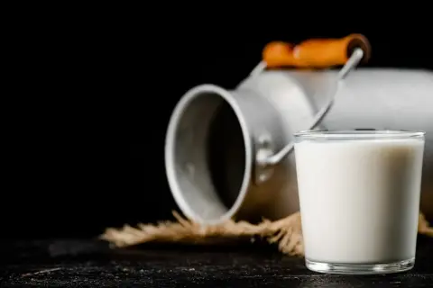 Szklanka mleka obok metalowego konewki. Czy to colostrum? To pierwszy, bogaty w składniki odżywcze pokarm matki.