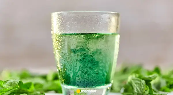 Szklanka z zielonym napojem, otoczona świeżą miętą. Zastanawiasz się nad picie chlorofilu efekty?