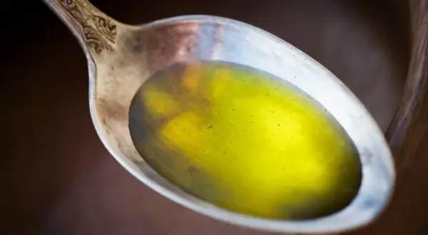 Łyżka z płynnym, żółtym olejem lnianym, który może pomóc w obniżeniu cholesterolu.