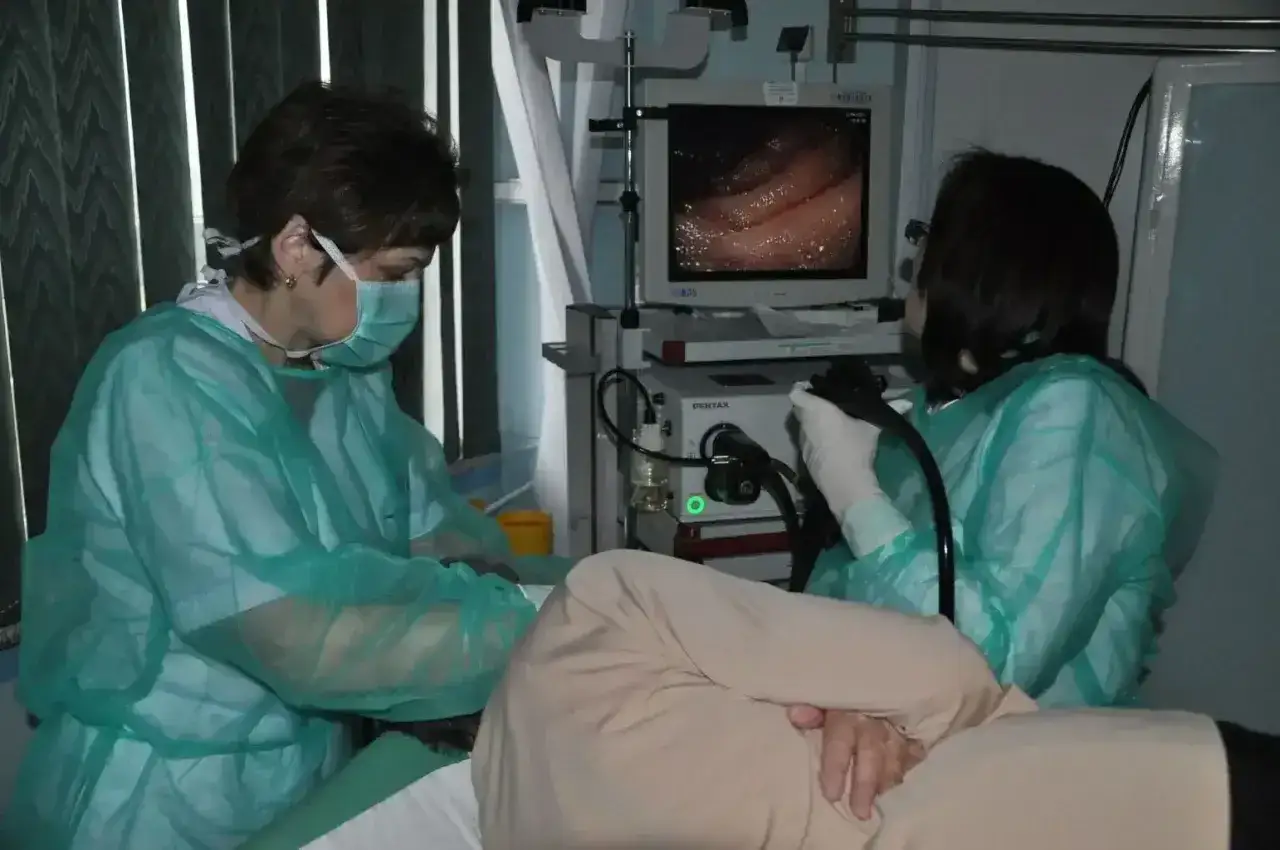 Lekarze w fartuchach i maskach przeprowadzają gastroskopię, monitorując obraz wnętrza żołądka, by wykryć ewentualne zmiany, np. spowodowane przez helicobacter pylori.