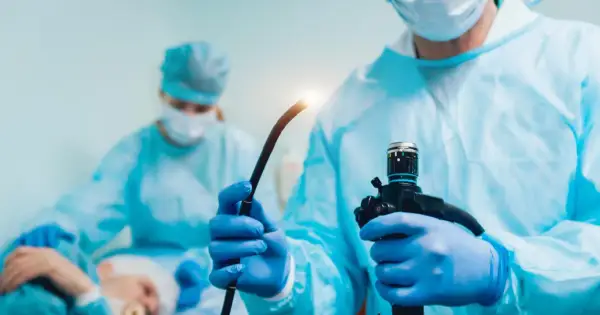 Lekarz w niebieskiej masce i fartuchu przygotowuje endoskop do badania, które może pomóc w diagnostyce przełyku Barretta.